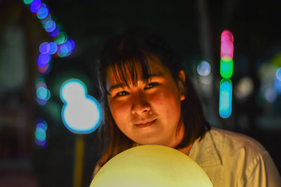 Portrait of woman with illuminated crystal ball at night