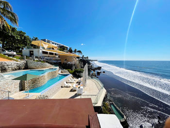 Swimming pool by sea against clear blue sky