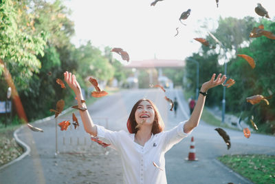 Woman with arms raised standing in background
