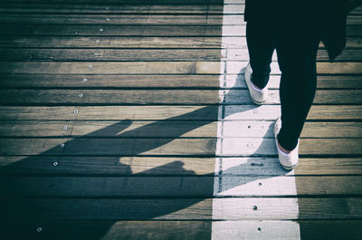 Low section of woman standing on boardwalk