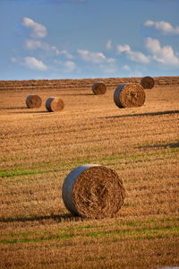 Hay bales on field against sky