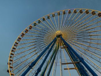 Low angle view of ferris wheel against clear blue sky