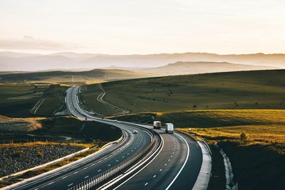 Country road leading towards mountains against sky