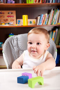 Cute baby boy playing with toys on table at home