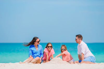 People on beach against clear blue sky