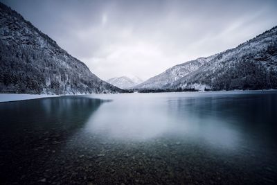Scenic view of lake by mountains against sky