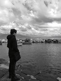 Rear view of man standing by sea against sky