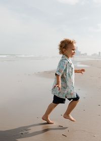 Portrait of girl standing at beach against sky