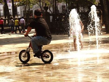 Rear view of man riding motorcycle on street in city