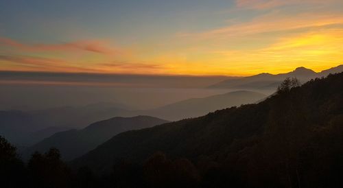 Scenic view of silhouette mountains against orange sky