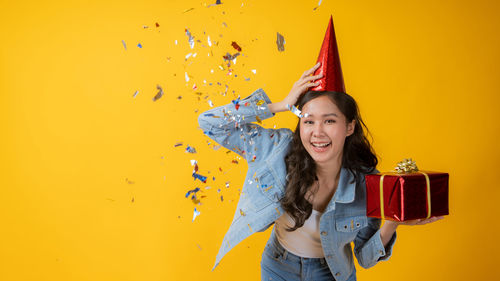 Portrait of a smiling young woman against yellow background