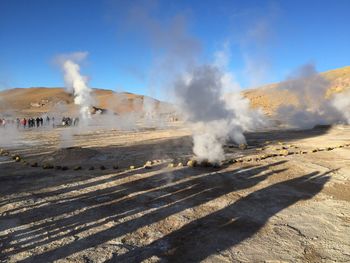 Smoke emitting from volcanic landscape against sky