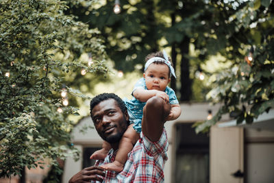 Father carrying daughter on shoulder outdoors