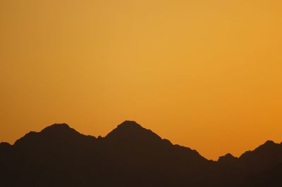 Silhouette mountains against orange sky