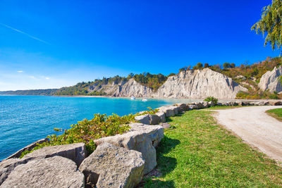Panoramic shot of rocks by sea against blue sky