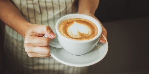 Midsection of barista holding coffee cup in cafe