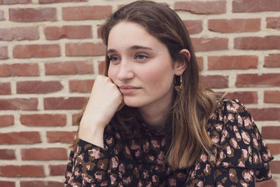 Young thoughtful woman against wall