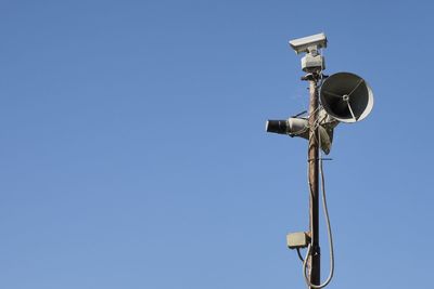 Low angle view of telephone pole against clear blue sky