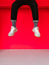 Low section of woman against red wall