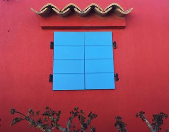 Low angle view of window on red wall