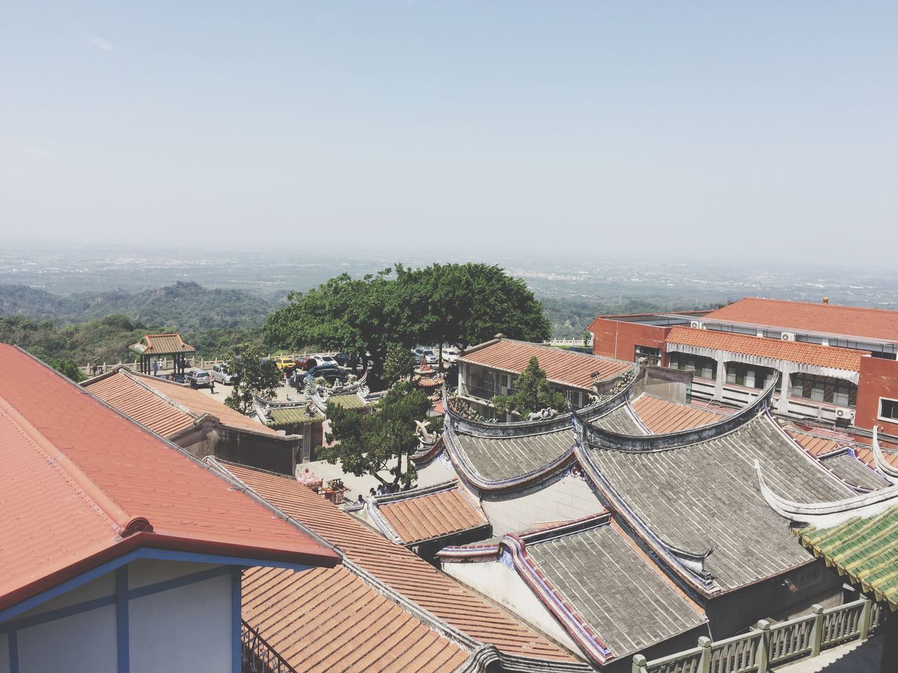 architecture, roof, building exterior, high angle view, tiled roof, built structure, no people, town, clear sky, day, outdoors, sky, city, cityscape, tree, residential