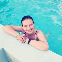 High angle portrait of smiling young woman in swimming pool