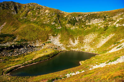 Scenic view of lake by mountain against sky