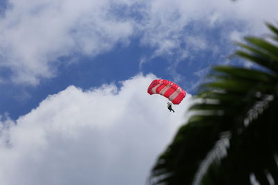 Low angle view of person paragliding against cloudy sky