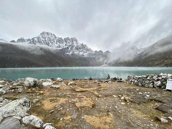 Scenic view of lake by snowcapped mountains against sky