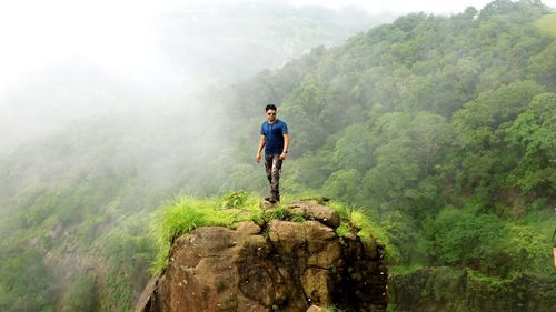 Portrait of man standing on rock against mountain