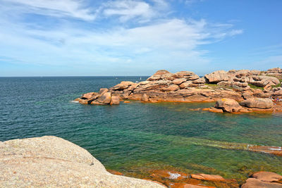 Rock formations by sea against sky