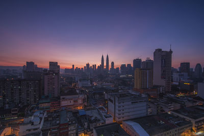 Distant view of petronas towers against sky during sunrise in city