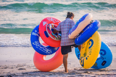 Rear view of man with inflatable ring walking at beach