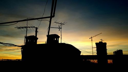 Low angle view of silhouette telephone pole against sky during sunset