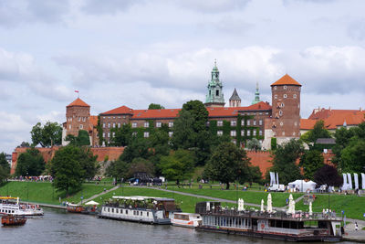 Buildings by river against sky