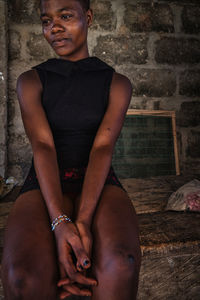 Portrait of woman sitting against wall