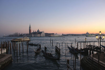 Boats moored in canal at sunset