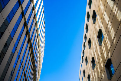 Low angle view of buildings against clear blue sky