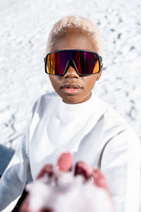 A young african american woman wearing sunglasses having fun in the snow on a winter day