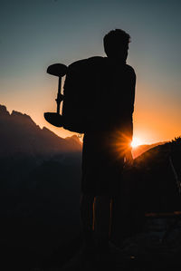 Silhouette man standing on mountain against sky during sunset