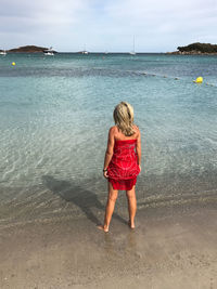 Rear view of woman on beach against sky