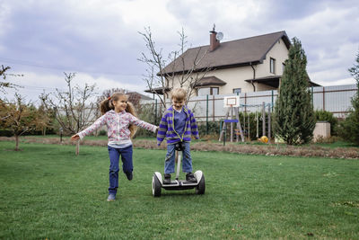 Children playing on land against house