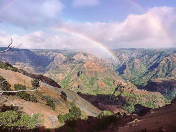 Scenic view of rainbow over mountains against sky