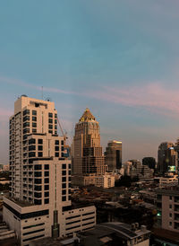 Buildings in city against sky during sunset