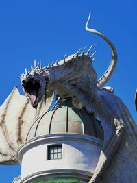 Low angle view of animal statue against clear blue sky