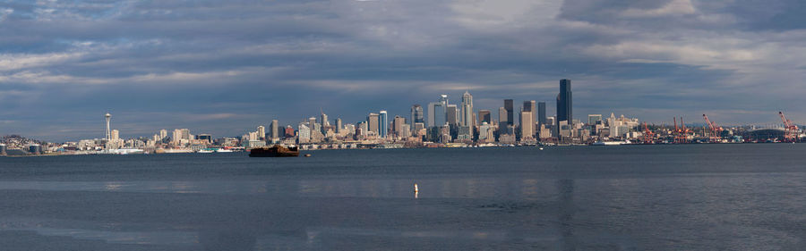 Sea by buildings against sky in city