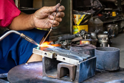 Cropped hands of man working on metal at workshop