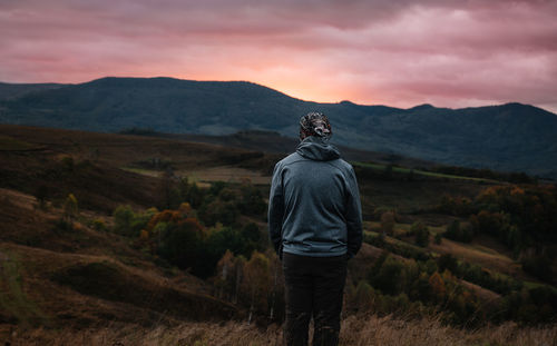 Man standing on mountain against sky during sunset