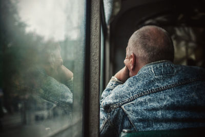 Rear view of man sitting near window of cable car