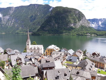 Church in town at lakeshore by mountains against sky